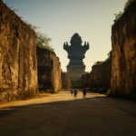 Area plaza terbuka di GWK Bali dengan dinding batu kapur dan patung menjulang di kejauhan pada sore hari